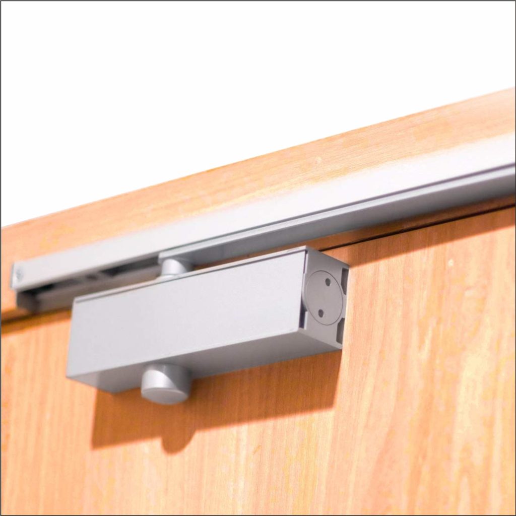 Automatic door closer installed on a light-colored wooden door frame