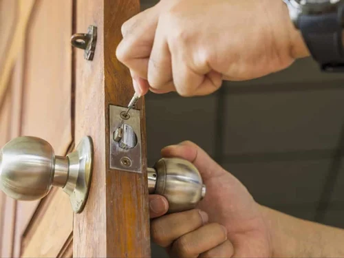 A person fixing a lock on a wooden door