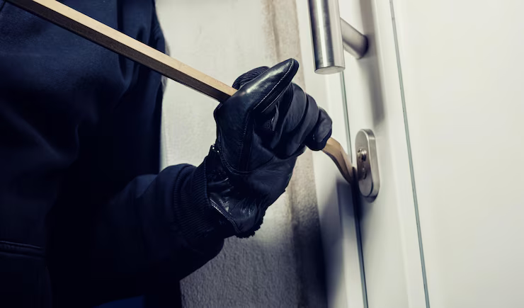 A burglar in black gloves grips a wooden stick, representing security concerns addressed by All in 1 Locksmith Services
