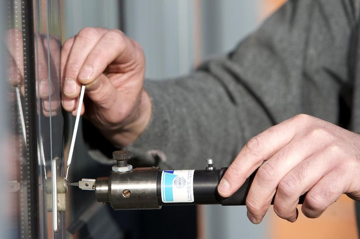 A person using a drill to open a residential door, demonstrating door repair services in action.