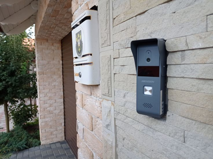 A wall-mounted telephone next to a metal fence, part of an intercom system installation.