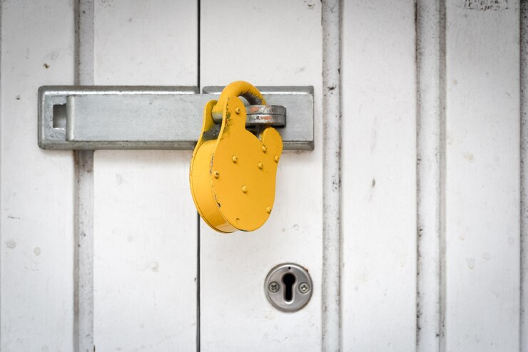 A yellow padlock fastened to a white door, highlighting the gate lock repair services