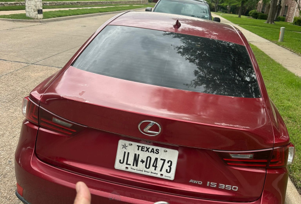 A person holding a key, standing next to a shiny red car, ready to unlock it.