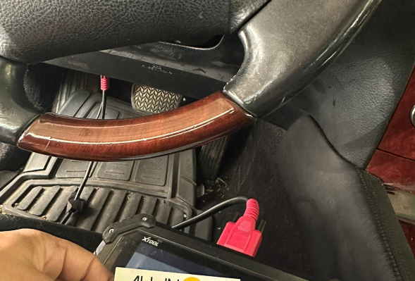 A person in a car's driver's seat holds a tablet, likely for key programming by All in 1 Locksmith.