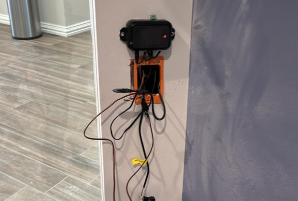 All in 1 Locksmith Electrical setup with wires and a device on a two-toned wall.