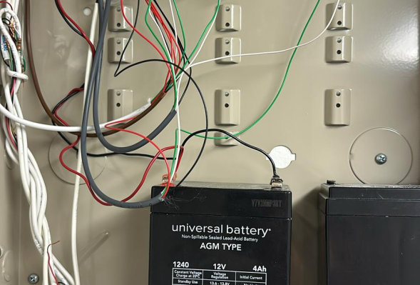 All in 1 Locksmith Interior of an electrical panel with a circuit board and two black batteries.