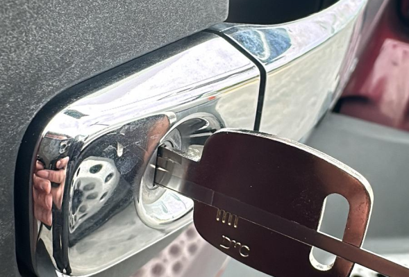 Close-up of a chrome vehicle door handle with a key inserted.